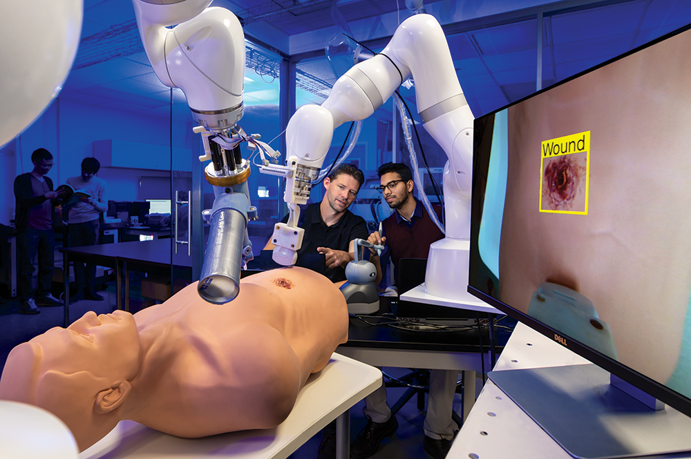 Assistant Professor Axel Krieger, at left, and master's student Anirudh Topiwala test a new robotic system for remote trauma assessment. Photo: John T. Consoli