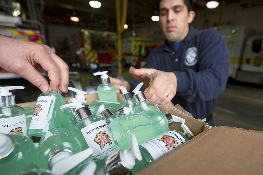 Firefighters Oscar Montalvo ’10, right, and Tyler Maccrone, hand at left, open a box of “Terpsanitizer,” hand sanitizer created by professors and students in the Department of Chemical and Biomolecular Engineering and donated to the Gaithersburg-Washington Grove Volunteer Fire Department. (Photos by Stephanie S. Cordle)