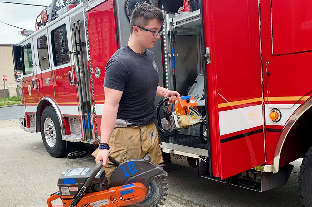 Jacob Nibali, one of 14 UMD student volunteers who are continuing to answer calls at the College Park Volunteer Fire Department amid the COVID-19 outbreak, checks saws to ensure they work properly and are full of fuel. Photo: Maddie Walstrum ’22