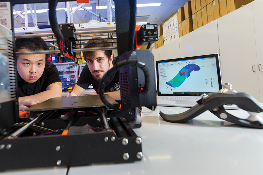 Karl Zhao (left) and a Terrapin Works staff member set up a 3D printer with the Stance, far right. Photo: John T. Consoli