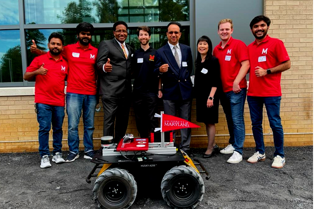 UMD President Darryll Pines and Professors Dinesh Manocha and Ming Lin pose with students in front of a robot that was featured in demos during opening ceremonies for the SMART Building.