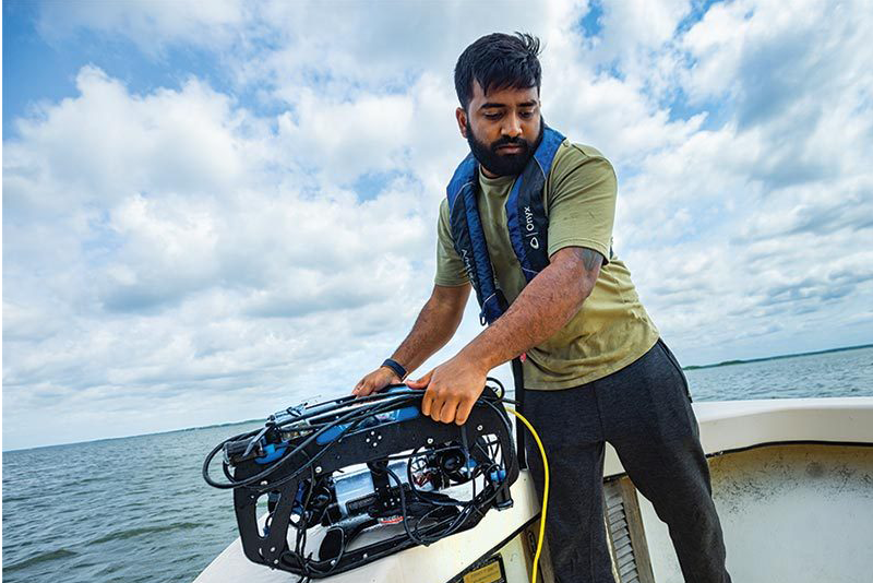 Keshav Rajasekaran Ph.D. ’22 prepares to launch an underwater robot to seek oysters. (Photo by Stephanie S. Cordle)