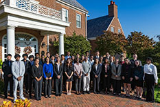 A group of students stand in front of a red brick building