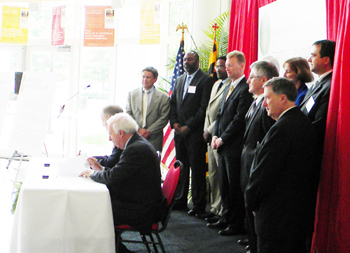 UM's Pres. Mote and Ray O. Johnson of Lockheed Martin sign the agreement as members of both organizations look on.