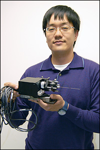 BioE graduate student Chia-Pin Liang holding the prototype Doppler Optical Coherence Tomography (DOCT) probe, which is designed to help surgeons navigate the brain and avoid damage to its blood vessels. Liang says that with further development, a handheld version could be created for other kinds of procedures in which doctors must guide tools deep into the body.