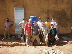 Most of the team with the clinic staff standing in front of the filter tanks.