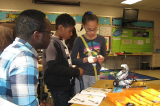 Malick Diarra works with students at Greenbelt Elementary School on building robots.